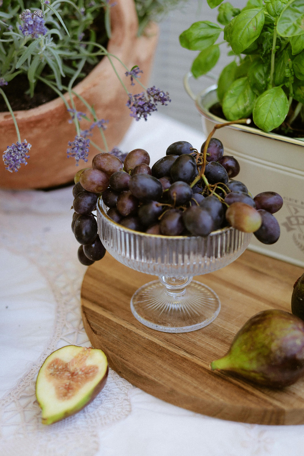 Fresh basil, herbs, grapes, and figs on a sunlit table